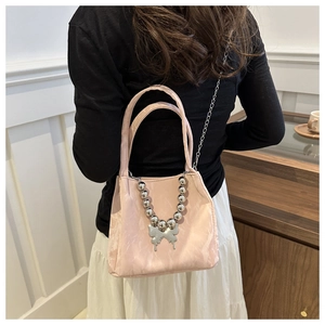 Rear view of a model wearing a pink pleated bucket bag with a butterfly charm and chain strap