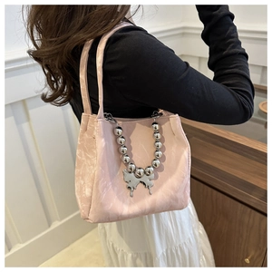 Close-up of pink bucket bag with silver bead chain and liquid metal butterfly charm detail