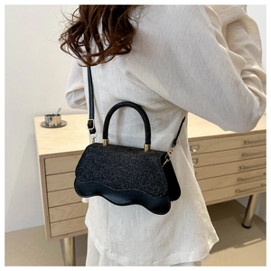 Elegant black sequin handbag with wavy edge detail and shoulder strap shown in a room