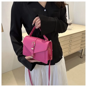 Détail du sac à bandoulière rose fuchsia avec fermoir doré porté par le mannequin