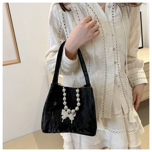 Close-up of black pleated bucket bag with silver bead chains and a metallic butterfly charm