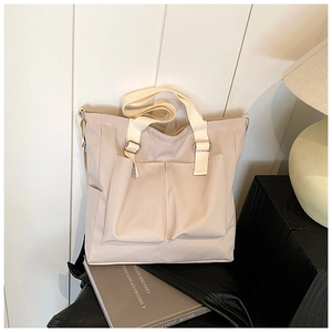Detail of beige canvas tote bag with front pockets and sturdy woven texture