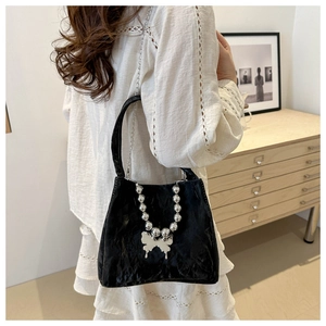 Elegant black bucket bag with ruffled texture and silver butterfly pendant detail