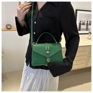 Modèle portant un sac enveloppe vintage en cuir vert émeraude à boucle dorée