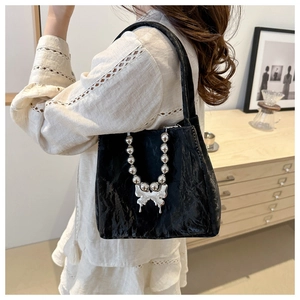 Detail of black wrinkled texture tote bag featuring silver butterfly pendant and bead chain