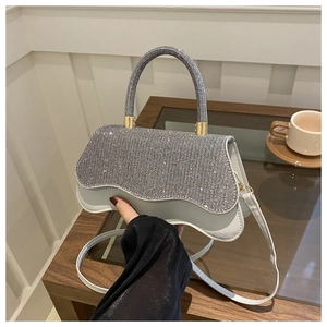 Detail of silver sequined handbag featuring a unique wavy base and sparkling rhinestones