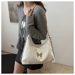 Close-up of white marble pattern underarm bag with silver butterfly metal decoration