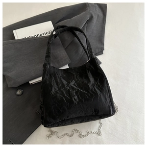 Detail of black wrinkled texture handbag with metallic silver chain and handles