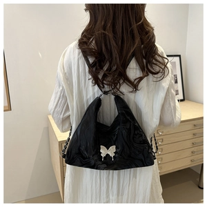Detail of black water-ripple tote bag with silver butterfly pendant and chain strap
