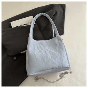 Close-up of pleated leather texture on a silver-blue bucket bag with metal chain link
