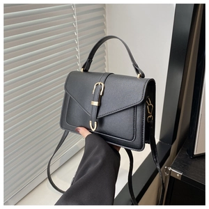 Gros plan d'un sac à bandoulière en cuir noir avec un fermoir doré élégant et raffiné