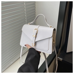 Détail d'un sac à bandoulière blanc vintage avec fermoir doré et poignée supérieure