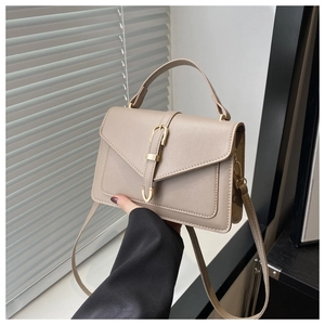 Détail d'un sac bandoulière en cuir beige avec boucle dorée élégante et poignée supérieure
