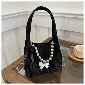 Detail of black velvet bucket bag with beaded handle, butterfly charm and silver chain