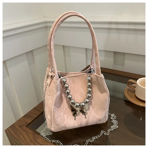 Detailed shot of pink pleated handbag with silver bead chain and butterfly charm
