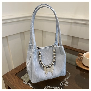 Detail of light blue bucket bag featuring pleated texture and silver butterfly pendant