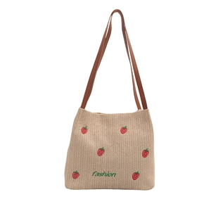 Large beige woven straw tote bag with strawberry embroidery and brown faux leather straps