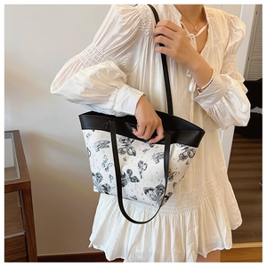 Elegant French butterfly print bucket bag with contrast black handles on female model