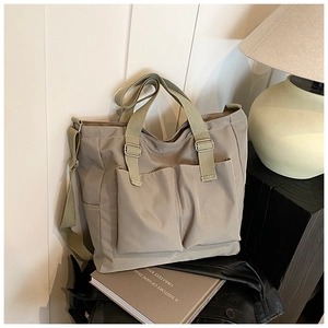 Detail of canvas tote bag with large front pockets and adjustable woven shoulder strap