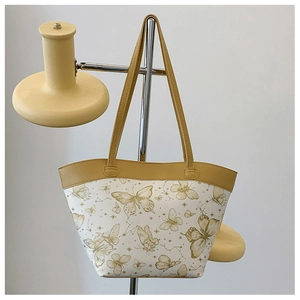Detail of white butterfly and constellation print tote bag with yellow leather handles