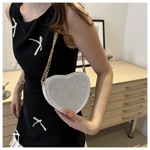 Dettaglio borsa a cuore con borchie argentate e tracolla a catena dorata