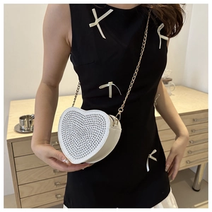 Dettaglio della borsa bianca a forma di cuore con strass luccicanti e catena dorata