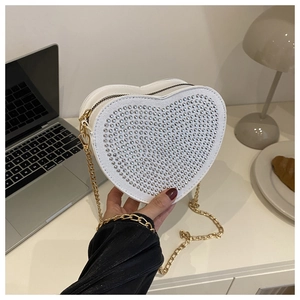 Dettaglio di una borsa bianca a forma di cuore con borchie argento e catena d'oro
