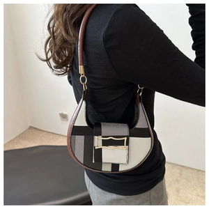 Detail of color-block crescent saddle bag featuring gold clasp and dark brown handle