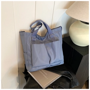 Detail of grey-blue nylon tote bag with functional front pockets in a stylish setting