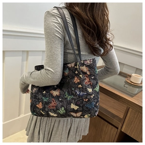 Detailed view of woven butterfly pattern on a canvas tote bag with black leather straps