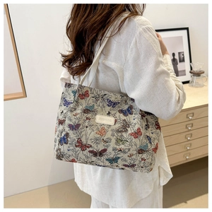 Detail of colorful butterfly embroidery on a large canvas tote bag shown in a lifestyle setting