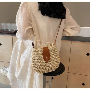 Borsa a tracolla in paglia intrecciata con patta in pelle su abito bianco a pieghe