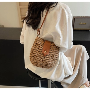 Dettaglio della borsa a tracolla in paglia intrecciata con patta in ecopelle marrone