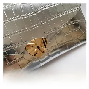 Détail macro du sac argenté texture crocodile avec fermoir métallique doré design