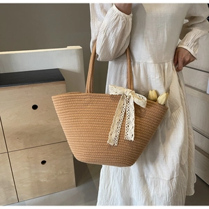 Detail of woven straw tote bag with elegant cream lace bow and natural cord texture