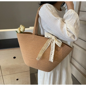 Straw woven tote bag with white lace bow detail for summer beach vacations and daily use