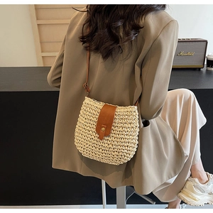 Dettaglio borsa in paglia intrecciata a mano con patta in pelle marrone e tracolla