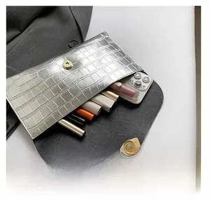 Pochette argentée à motif crocodile montrant la capacité intérieure pour portable et rouge à lèvres