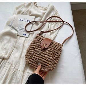 Dettaglio borsa in paglia intrecciata con patta in pelle marrone e chiusura in metallo