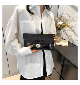 Gros plan sur la pochette enveloppe noire à motif crocodile et fermoir doré
