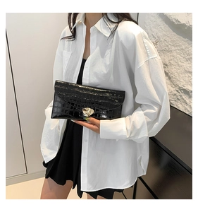 Détail de pochette noire motif crocodile avec fermoir en métal doré en forme de cœur