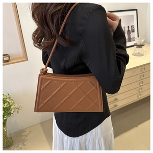 Détail du sac à bandoulière matelassé marron avec texture cuir et nœud de sangle chic