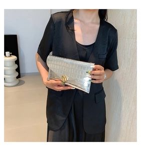 Détail d'un sac à main argenté à relief crocodile avec boucle métallique en forme de cœur
