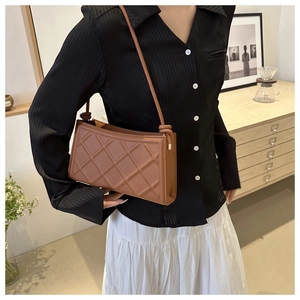 Détail d'un sac bandoulière marron matelassé avec un nœud élégant sur la lanière en cuir