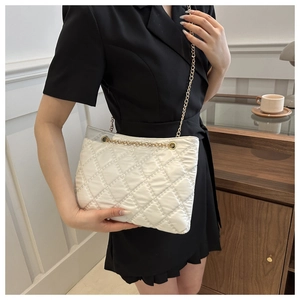 Detail of white quilted shoulder bag with elegant gold chain strap and stitching