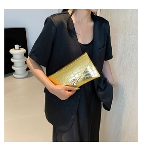 Gros plan sur pochette dorée motif crocodile avec boucle géométrique argentée