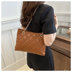 Rear view of model wearing a brown quilted tote bag with gold chain shoulder strap