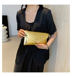 Détail de la pochette enveloppe dorée à motif crocodile avec texture métallique chic