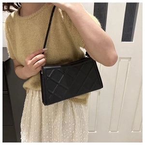Sac à bandoulière en cuir matelassé noir porté par un mannequin au style moderne