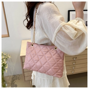 Detailed view of pink quilted rhombus tote bag with gold chain strap on shoulder